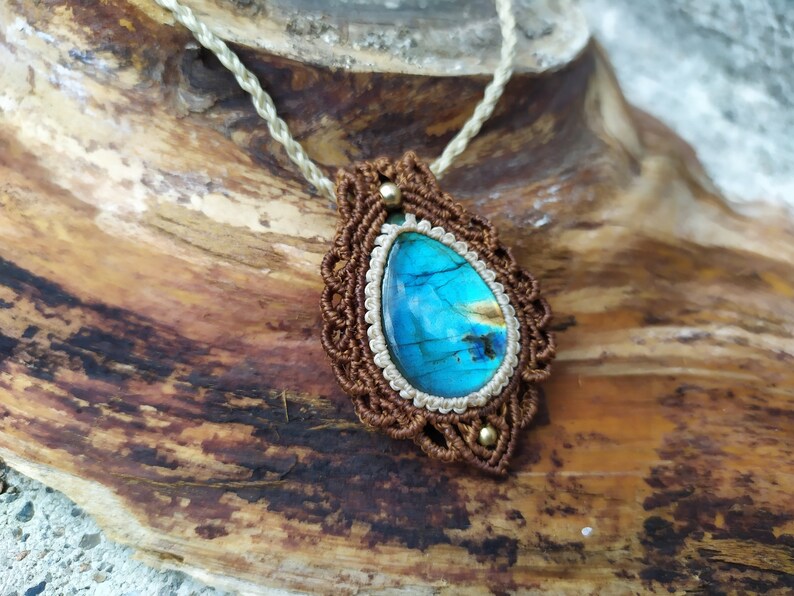 May include: A brown and white macrame necklace with a blue labradorite gemstone pendant.