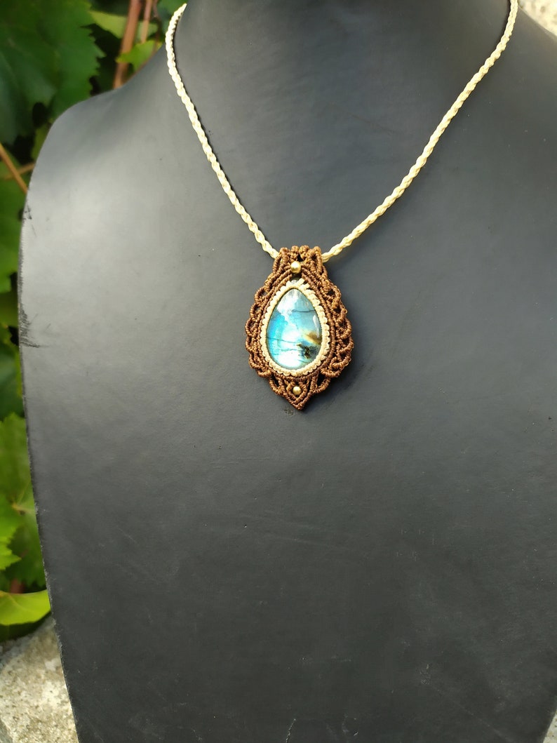 May include: A brown macrame necklace with a teardrop-shaped blue labradorite gemstone pendant.