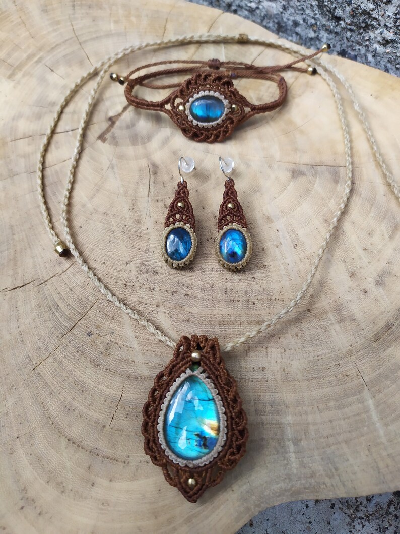May include: A set of jewelry featuring a brown macrame necklace, bracelet, and earrings with iridescent blue labradorite stones.