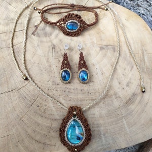 May include: A set of jewelry featuring a brown macrame necklace, bracelet, and earrings with a blue labradorite gemstone pendant.