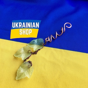 May include: A copper wire hair clip with a spiral design and three green glass leaves attached. The clip is on a yellow and blue background with the text "UKRAINIAN SHOP".