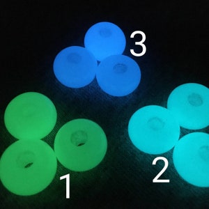 May include: A close-up of nine glow-in-the-dark beads. Three beads are blue, three are green, and three are a light blue-green color. The beads are arranged in a circle with the numbers 1, 2, and 3 written on the image.