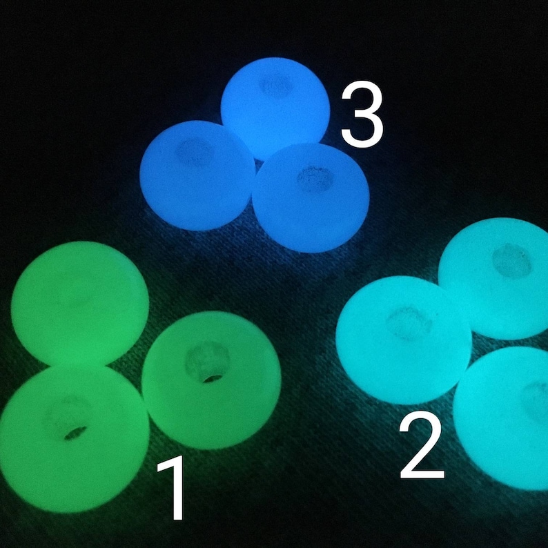 May include: A close-up of nine glow-in-the-dark beads. Three beads are blue, three are green, and three are a light blue-green color. The beads are arranged in a circle with the numbers 1, 2, and 3 written on the image.