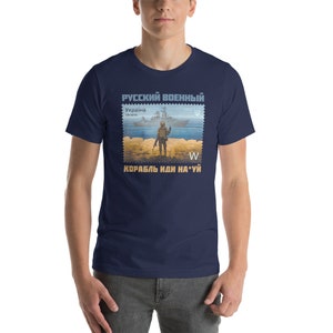 May include: Navy blue t-shirt featuring a postage stamp design with a soldier, ship, and text in Russian and Ukrainian. The stamp includes the text "Russian Military" and "Ukraine". The shirt has a crew neck and short sleeves.