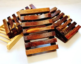 May include: Three wooden soap dishes, two are stacked on top of each other. The top dish is a dark brown colour and has a slatted design. The bottom dish is a lighter brown colour and has a more open design.