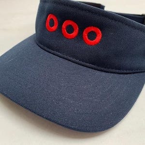 May include: A navy blue visor with red embroidered "OOO" lettering.