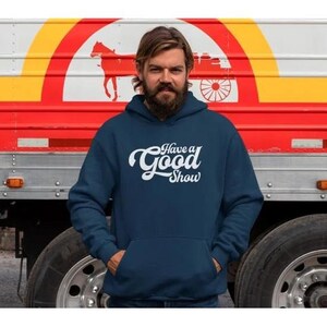 Può includere: Una felpa con cappuccio blu navy con una grafica bianca che dice "Have a Good Show" in un font retrò.