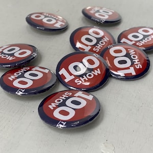 May include: A collection of red and blue round buttons with the text "100 SHOW" and "100 MOHS" printed on them.