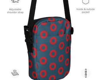 May include: A teal crossbody bag with a repeating pattern of red circles. The bag features an adjustable shoulder strap, a two-way zipper, and an inside and outside pocket. The bag is made of sturdy fabric.