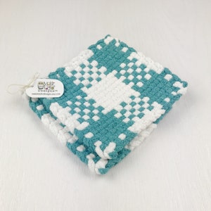 May include: Two square, hand-woven washcloths in a teal and white checkered pattern. The washcloths are folded and stacked, with a tag attached that reads "Maisie Taylor Designs" and the Etsy shop URL.