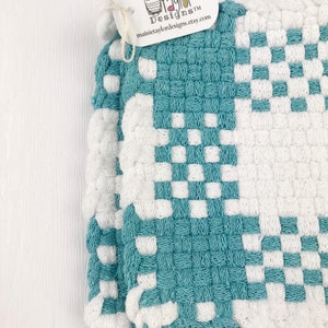 May include: A teal and white woven potholder with a checkerboard design. The tag attached reads "Maisie Taylor Designs" and the website maisietaylordesigns.etsy.com.