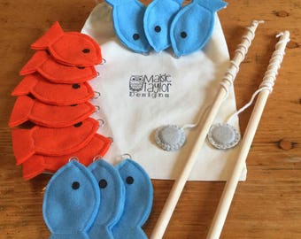 May include: A felt fishing game with two wooden fishing rods, blue and orange felt fish, and a white drawstring bag with the text "Maisie Taylor Designs".