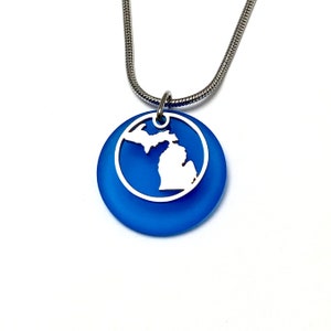 May include: A blue glass pendant necklace with a silver outline of the state of Michigan.