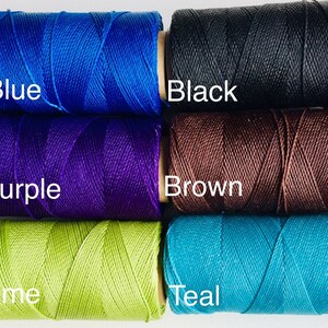 May include: Five spools of thread in different colors: blue, purple, brown, lime green, and teal. The spools are labeled with the color names.