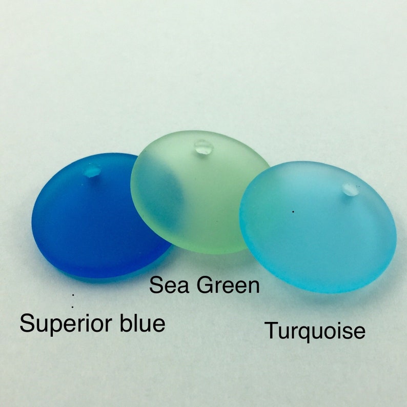 May include: Three round glass beads in shades of blue and green. The beads are labelled "Superior blue", "Sea Green", and "Turquoise".