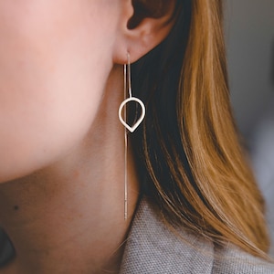 以下が含まれることがあります： 繊細なチェーンがぶら下がった、銀製の涙滴型のイヤリングのペアです。