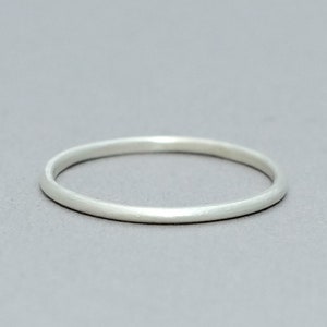 May include: A simple silver band ring.