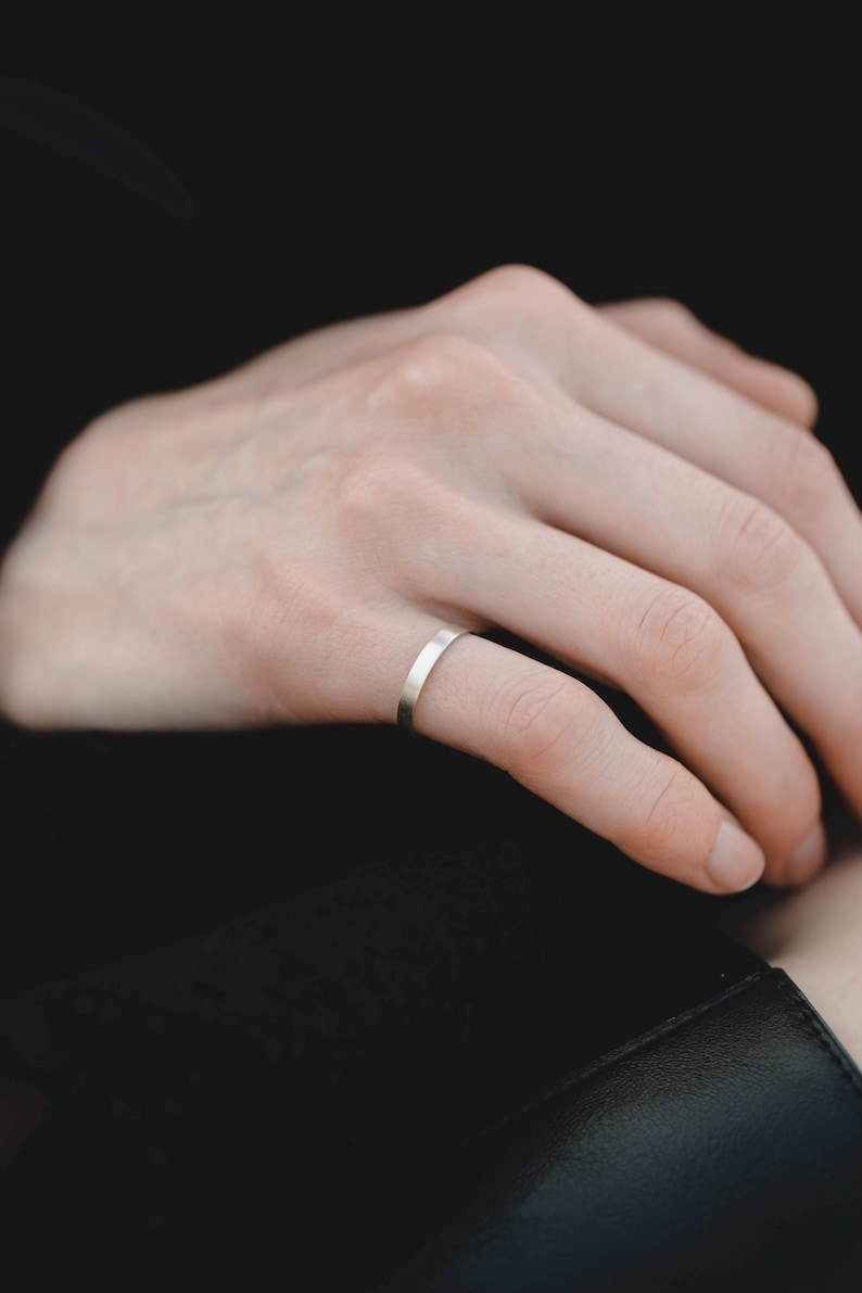 Op de afbeelding: Een close-up van een hand met een dunne zilveren ring.