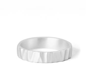 May include: A silver-colored ring with a textured, uneven outer surface featuring vertical indentations. The band has a consistent width and a matte finish, creating a series of subtle ridges around the entire circumference of the circular jewelry piece.