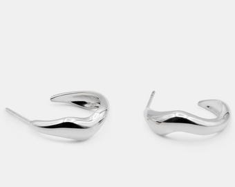 May include: A pair of silver hoop earrings with a unique, wavy, organic shape.