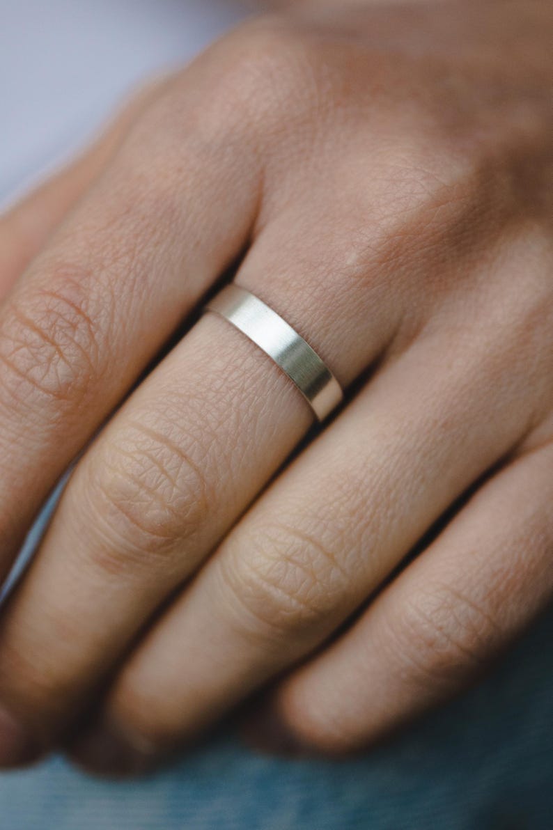 Op de afbeelding: Een eenvoudige zilveren ring gedragen aan een vinger.