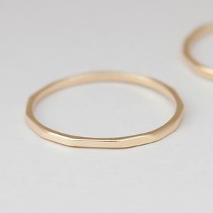 May include: Two gold hammered rings, one is slightly larger than the other. The rings are simple and have a matte finish.