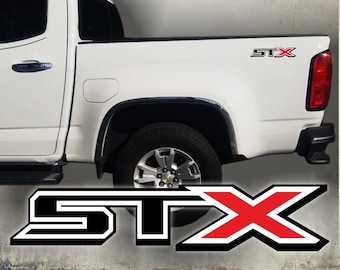 May include: White pickup truck with a black and red "STX" decal on the side. The decal is in a bold, blocky font.