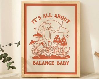 May include: A framed print with a white background and orange text that reads "It's all about balance baby". The image features a cat riding a unicycle with mushrooms in the background.