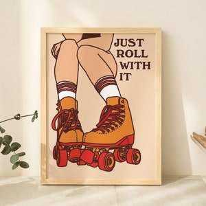 May include: A framed illustration of a person wearing roller skates with the text "JUST ROLL WITH IT" in brown lettering on a light peach background.
