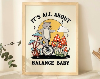 May include: A framed print with a cat riding a unicycle surrounded by mushrooms. The text reads "It's all about balance baby".