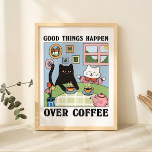May include: A framed print with a black cat and a white cat sitting at a table with cups of coffee. The text on the print reads "Good things happen over coffee."