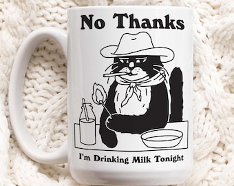 May include: White ceramic mug with a black and white illustration of a cat wearing a cowboy hat and smoking a cigarette. The text "No Thanks I'm Drinking Milk Tonight" is printed on the mug.