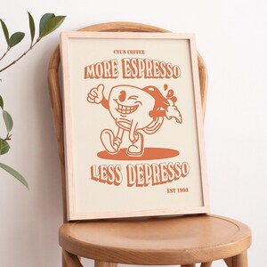 K&ouml;nnte beinhalten: Ein gerahmter Druck mit einer Cartoon-Illustration einer Kaffeetasse mit einem l&auml;chelnden Gesicht. Der Text lautet "CYUN COFFEE MORE ESPRESSO LESS DEPRESSO EST 1993".