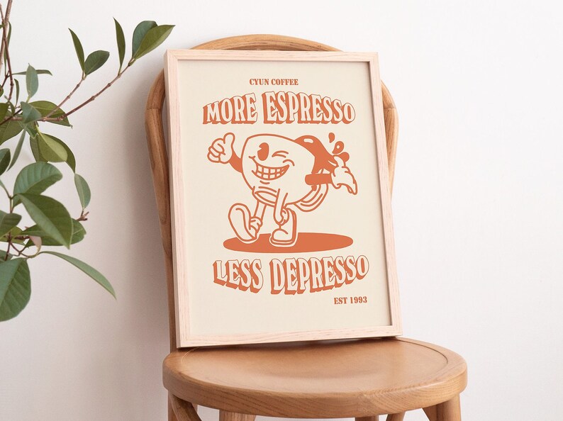 K&ouml;nnte beinhalten: Ein gerahmter Druck mit einer Cartoon-Illustration einer Kaffeetasse mit einem l&auml;chelnden Gesicht. Der Text lautet "CYUN COFFEE MORE ESPRESSO LESS DEPRESSO EST 1993".