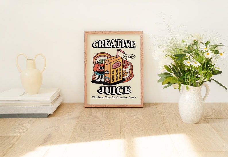 May include: A framed print with a retro illustration of a cartoon orange juice carton with a brain inside. The text reads "Creative Juice: The Best Cure for Creative Block".