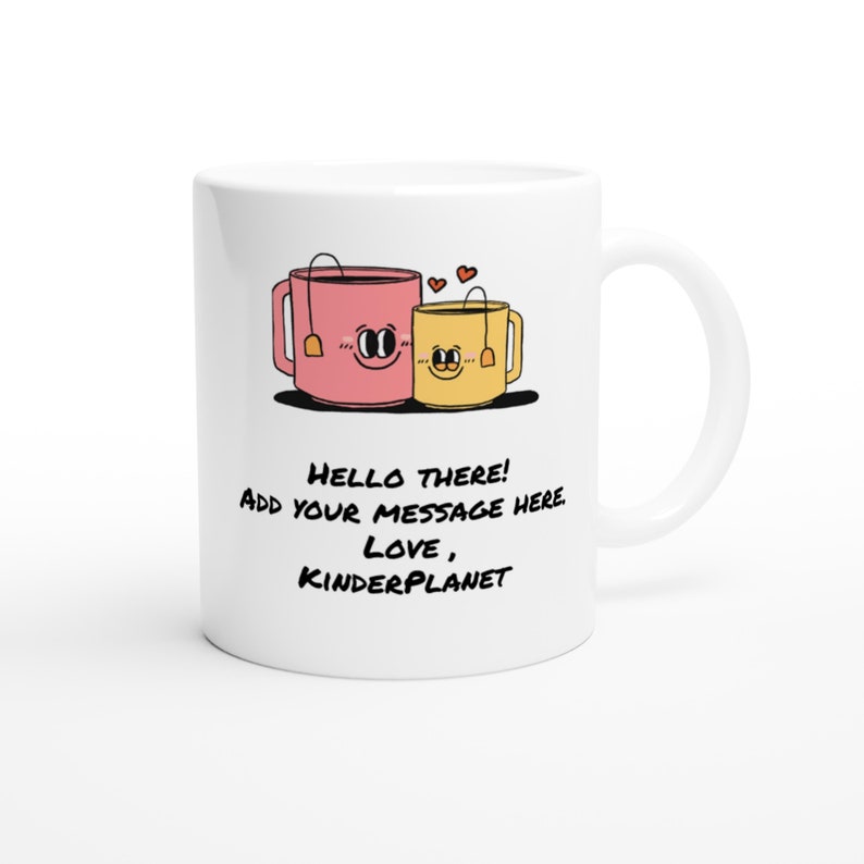May include: White ceramic mug with a pink and yellow cartoon teacup design. The teacups have faces and are holding hands. The text on the mug reads "Hello there! Add your message here. Love, Kinderplanet."