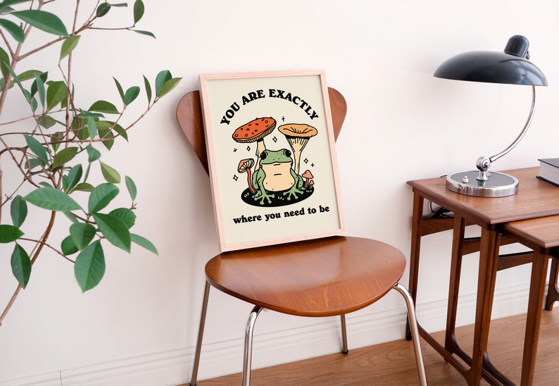 May include: A framed print featuring a green frog sitting on a mushroom with the text "You are exactly where you need to be".