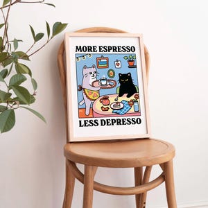 May include: A framed print with a cartoon illustration of two cats. One cat is serving the other cat a cup of coffee. The text on the print reads "More Espresso Less Depresso".