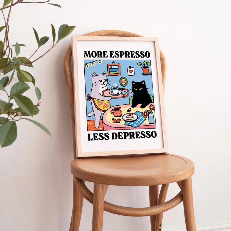 May include: A framed print with a cartoon illustration of two cats. One cat is serving the other cat a cup of coffee. The text on the print reads "More Espresso Less Depresso".