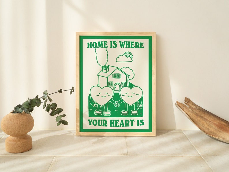 May include: A framed green and white print with the text "Home is where your heart is". The print features a cartoon house with two hearts holding hands in front of it.