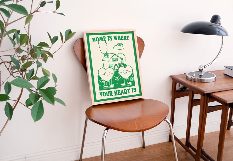 May include: A green and white poster with the text "Home is where your heart is". The poster features a cartoon house with two hearts holding hands in front of it.