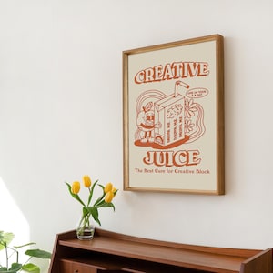 May include: A framed print with a retro-style illustration of a cartoon juice box with a brain inside. The text on the print reads "Creative Juice" and "The Best Cure for Creative Block".