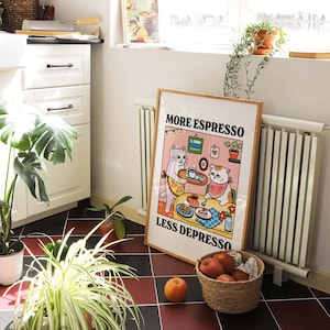 May include: A white poster with a cartoon illustration of two cats drinking coffee. The poster has the text "More Espresso Less Depresso" in black letters.