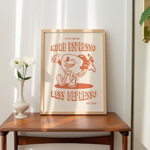 K&ouml;nnte beinhalten: Ein gerahmter Druck mit einer orangefarbenen Comic-Kaffeetassenfigur. Der Text lautet "CYUN COFFEE MORE ESPRESSO LESS DEPRESSO EST 1993".