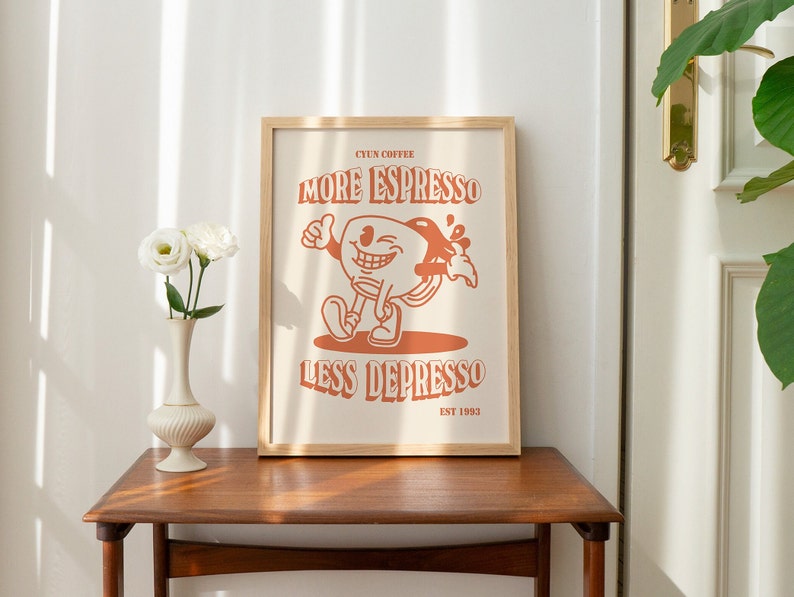 K&ouml;nnte beinhalten: Ein gerahmter Druck mit einer orangefarbenen Comic-Kaffeetassenfigur. Der Text lautet "CYUN COFFEE MORE ESPRESSO LESS DEPRESSO EST 1993".