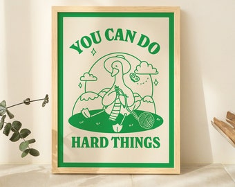 May include: A green and white illustrated poster with a duck holding yarn and a ball of yarn. The poster says "You can do hard things".