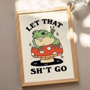 Pu&ograve; includere: Una stampa incorniciata con una rana di cartone animato seduta su un fungo. La rana sta facendo il segno della pace e il testo dice "Let That Sh*t Go".