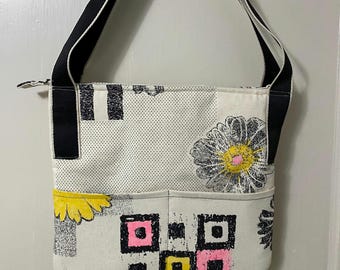 Fabric summer handbag lightweight roomy inside with four outside pockets .Black straps and a zipper closure .