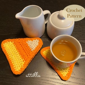 May include: Two crocheted orange, yellow, and white triangle coasters with a white teapot and a white creamer on a dark wood surface. The text "Crochet Pattern" is written in a brown circle on the image.