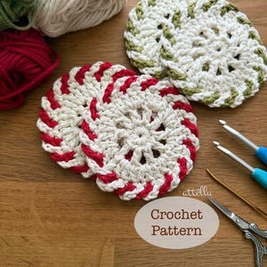 May include: Handmade crochet coasters in white with red and green detailing. The coasters have a circular shape and a spiral pattern. The image also shows balls of yarn in red, white, and green, plus crochet hooks and scissors. The text "Crochet Pattern" is visible.